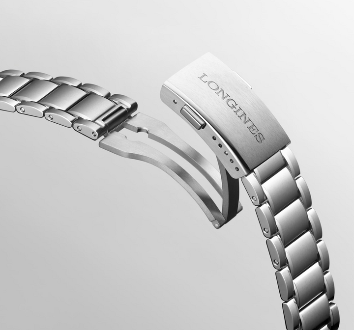 A close-up of a Longines watch angled showing the stainless steel bracelet and undone clasp. The Longines logo is engraved the clasp.