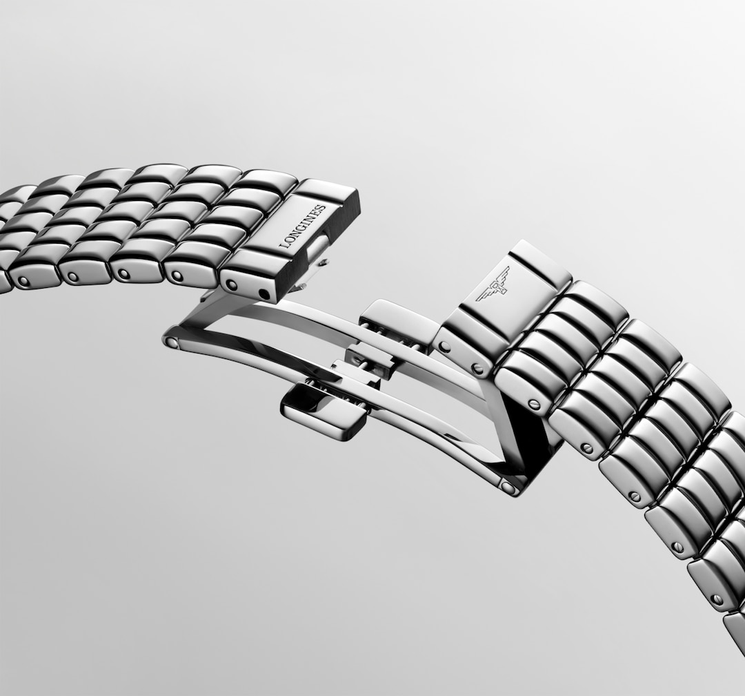 A close-up of a Longines watch showcasing the watch's stainless steel bracelet clasp undone.