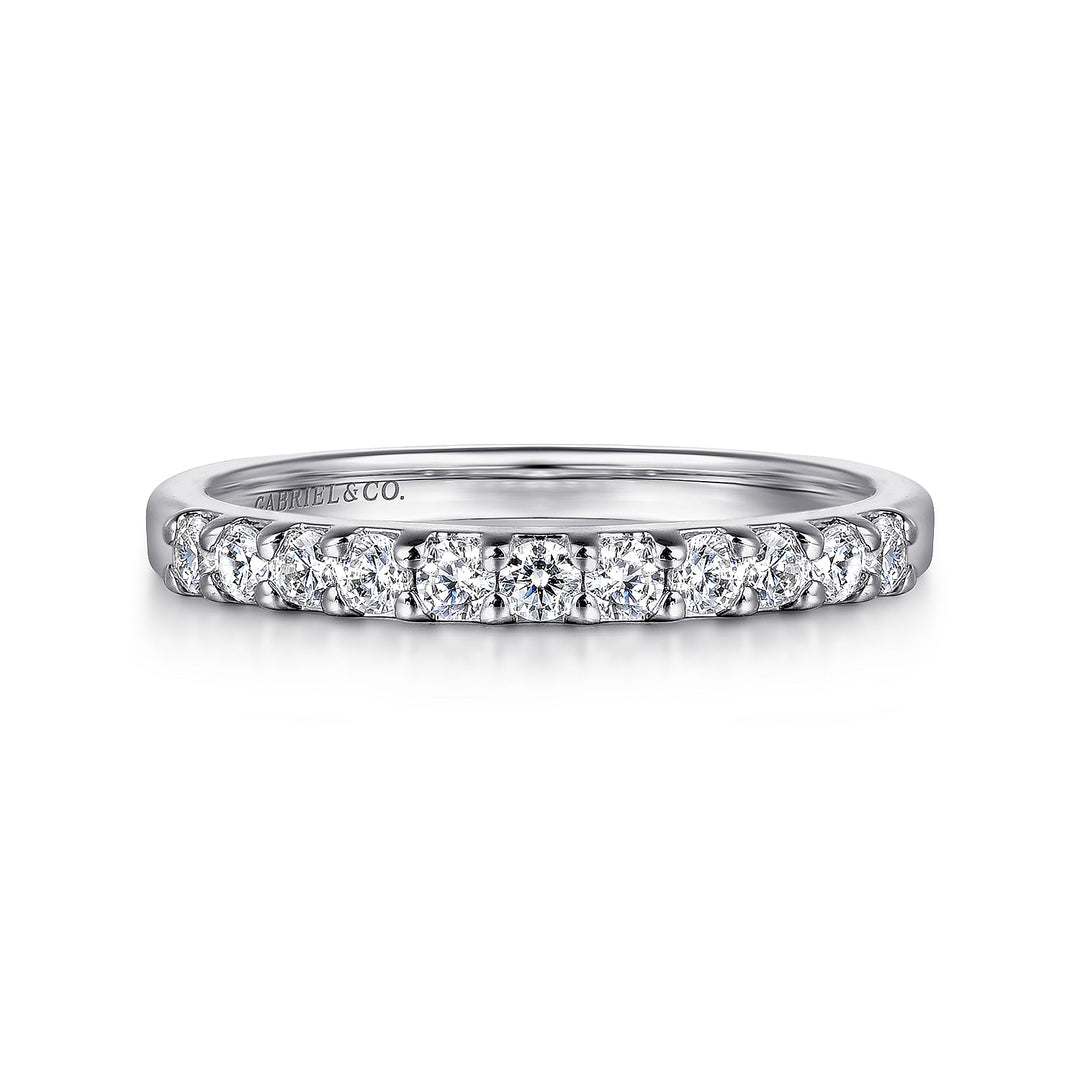 A white gold ring lies flat against a white background. The band features eleven round-cut diamonds in a straight line.