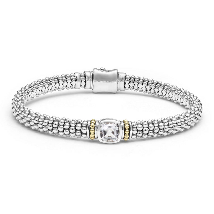 A sterling silver bracelet in the middle of a white background features a white topaz gemstone and sterling silver Caviar beading with 18K gold detailing.