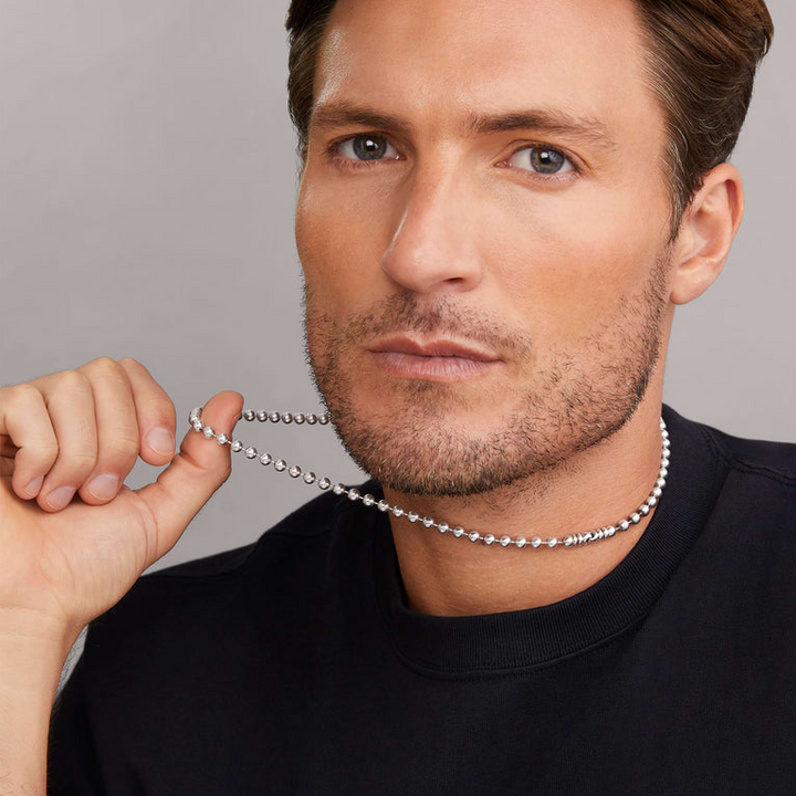 A man is wearing a Sterling Silver & 18K Gold necklace in the middle of a white background, featuring Caviar beading and fluted accents