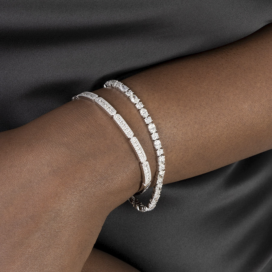 A woman is wearing a black satin dress and a bracelet made of 14k white gold with a pave diamond cluster design.