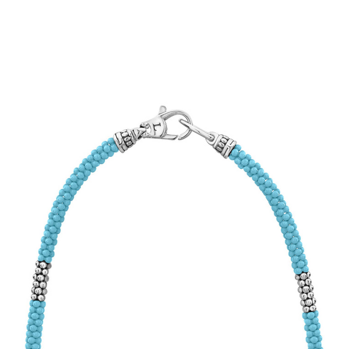 A sterling silver and ceramic beaded necklace in the middle of a white background featuring light blue ceramic and silver caviar beading highlights the lobster clasp.