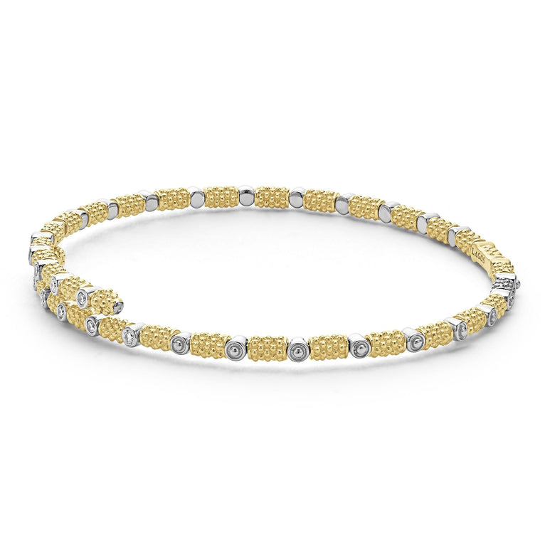 An 18K gold cuff bracelet angled laying in the middle with a white background, featuring caviar beading and diamonds