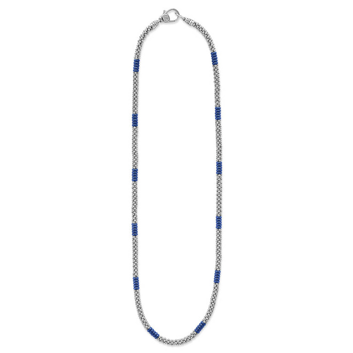 A sterling silver and ceramic beaded necklace in the middle of a white background featuring blue ceramic and silver Caviar beading.