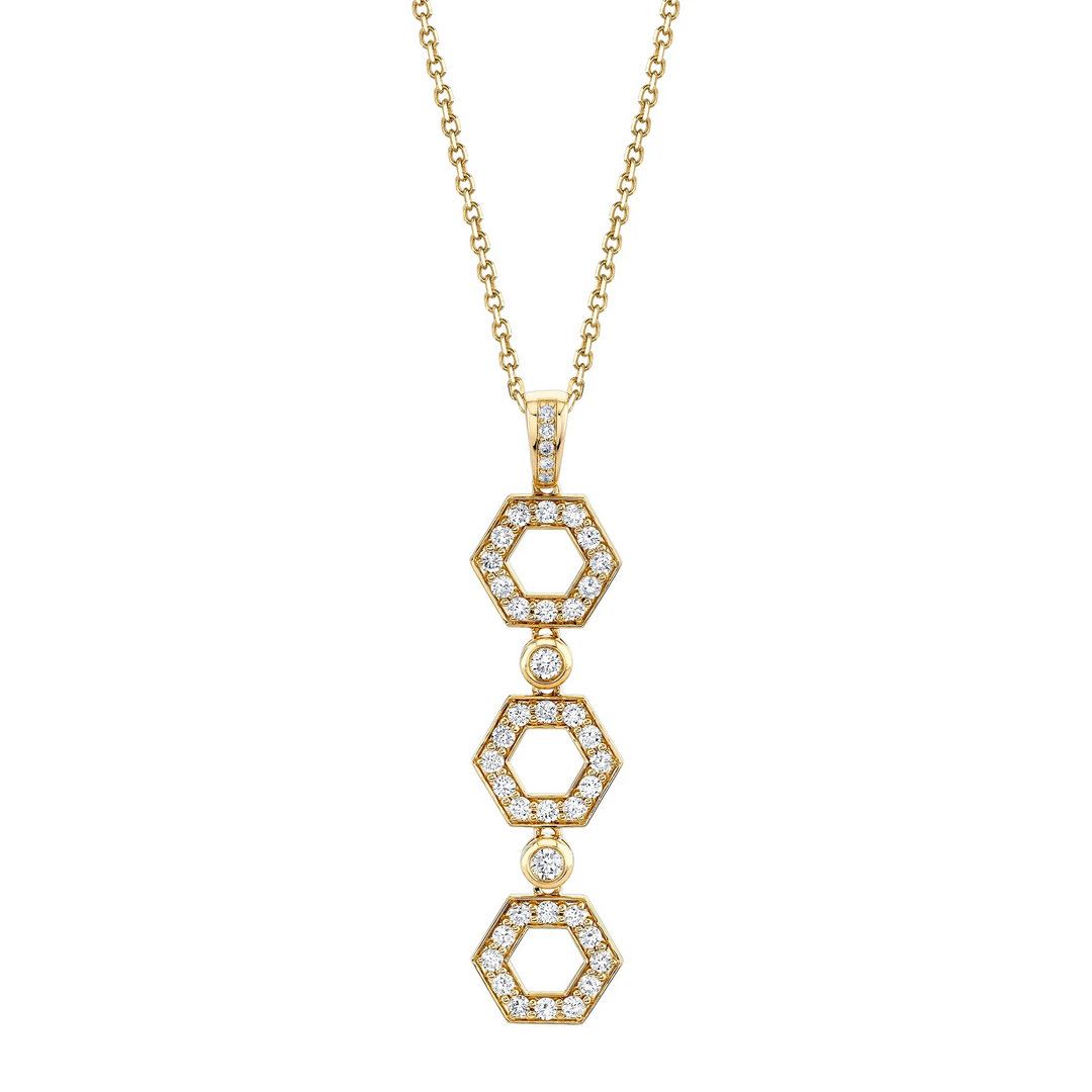 A yellow-gold necklace lying flat against a white background features three hexagon motif pendants with round bezel-set diamonds.