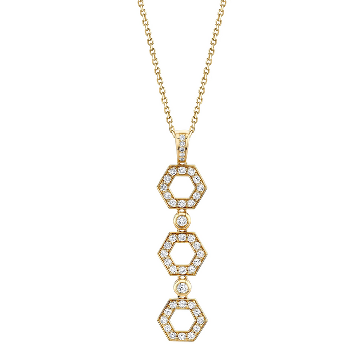 A yellow-gold necklace lying flat against a white background features three hexagon motif pendants with round bezel-set diamonds.