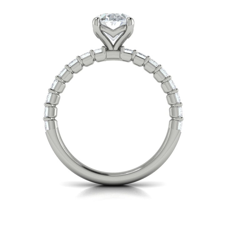 A top view of a white gold engagement ring is set against a white background. The engagement ring features an oval-shaped center stone, raised in the Vlora signature V-setting, with emerald-cut accent diamonds blazing across the band.