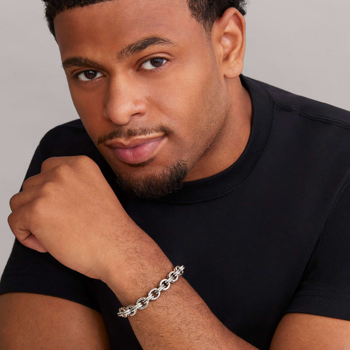 A man is wearing a sterling silver bracelet featuring a double link chain and krunch crescent on the clasp