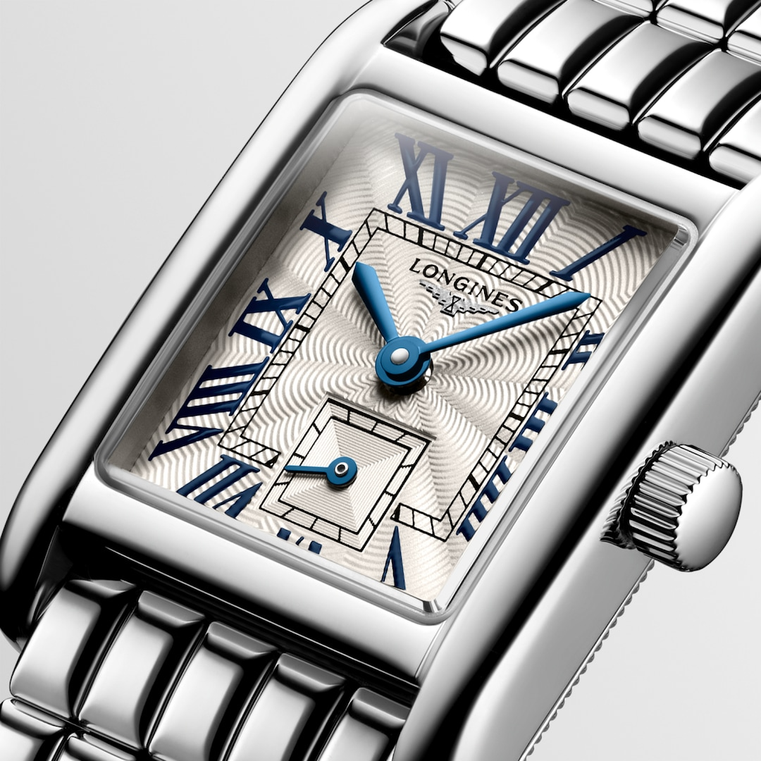 This is a close-up of a Longies watch angled to the right, showcasing the dial with a white background. The rectangular-shaped watch features a silver dial, blue hands, black markers, a stainless steel bezel, and a stainless steel bracelet.