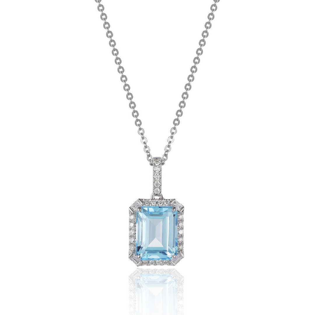 A close-up of a white-gold Delicate Emerald Cut Necklace against a white background. The necklace features a cushion-cut blue topaz center stone and an 18k white gold chain.