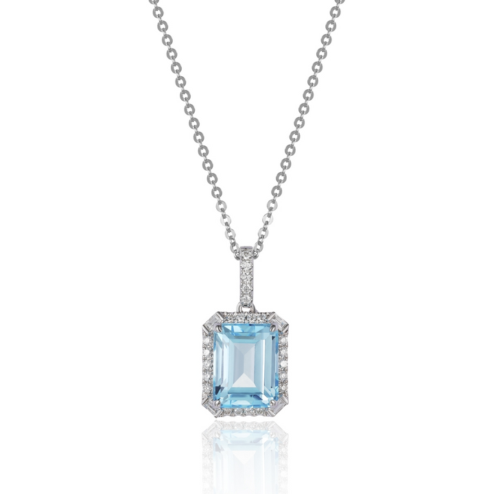 A close-up of a white-gold Delicate Emerald Cut Necklace against a white background. The necklace features a cushion-cut blue topaz center stone and an 18k white gold chain.