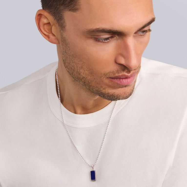 A man wearing a Lapis Tag Amulet with a chain necklace