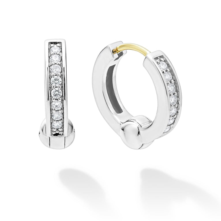 A pair of huggie earrings with diamonds set in a smooth sterling silver circle motif. The right earring is angled to the side.