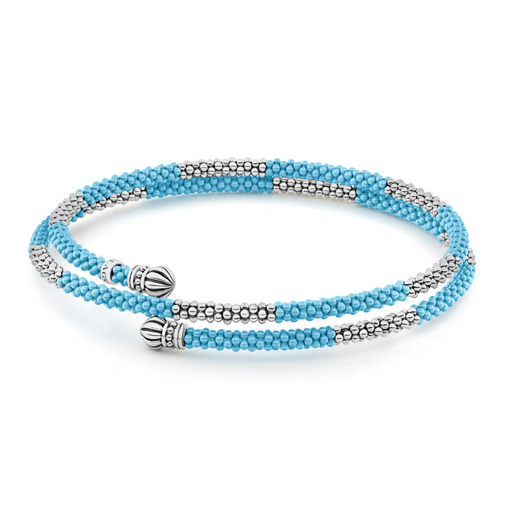 A sterling silver bracelet in the middle of a white background featuring ten sterling silver stations highlighted by blue ceramic Caviar beading finished with fluted sterling silver endcaps