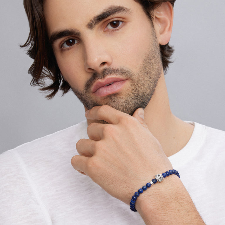 A man is wearing a sterling silver bracelet featuring a Lapis gemstone beaded bracelet with a silver Caviar skull.