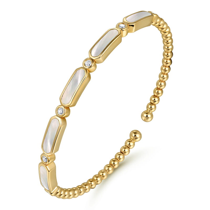 Angled view of the Gabriel & Co Bujukan bangle showing its mother-of-pearl stations and beaded yellow gold band.