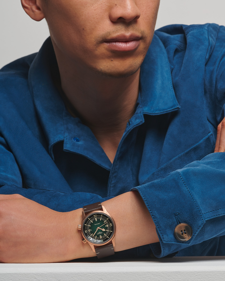 man wearing a LONGINES Legend Diver Bronze watch with a dark green dial and a brown leather strap.