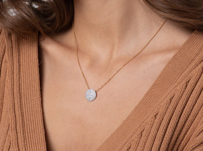 Model wearing the Medium Infinity diamond disc necklace with a brown V-neck sweater