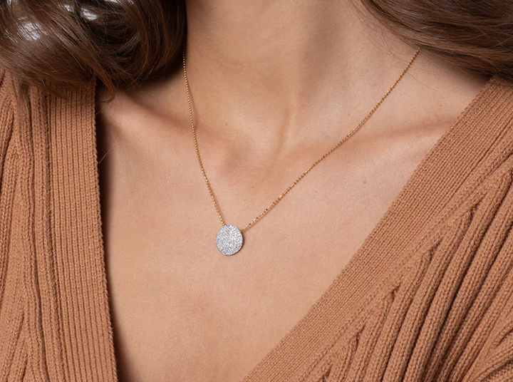 Model wearing the Medium Infinity diamond disc necklace with a brown V-neck sweater
