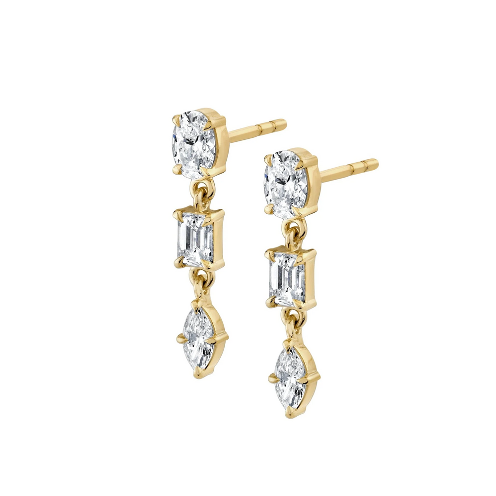 A pair of yellow gold earrings against a white background, both earrings are angled and positioned on their sides. The earrings feature a drop design with oval, emerald, and marquise-cut diamonds.