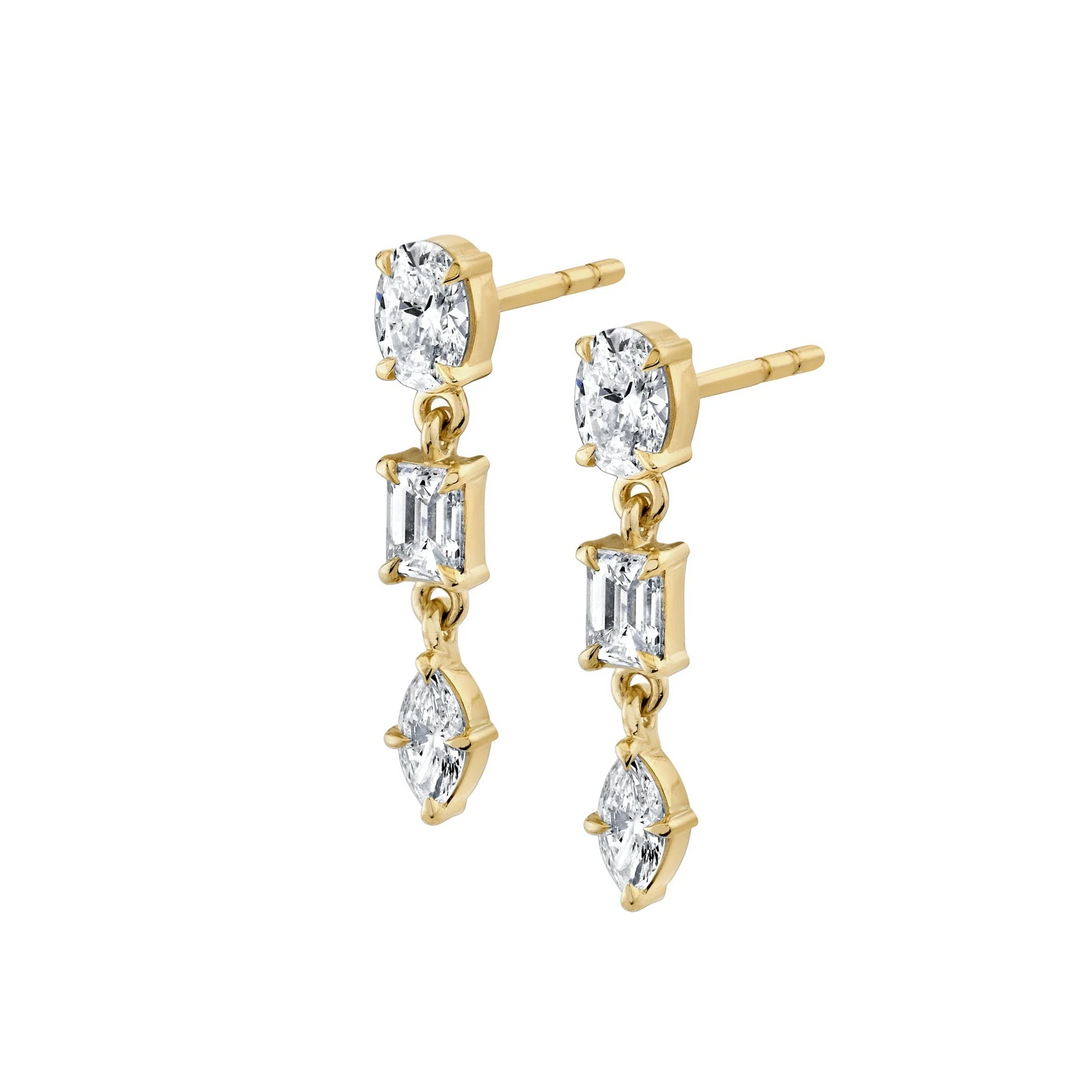 A pair of yellow gold earrings against a white background, both earrings are angled and positioned on their sides. The earrings feature a drop design with oval, emerald, and marquise-cut diamonds.