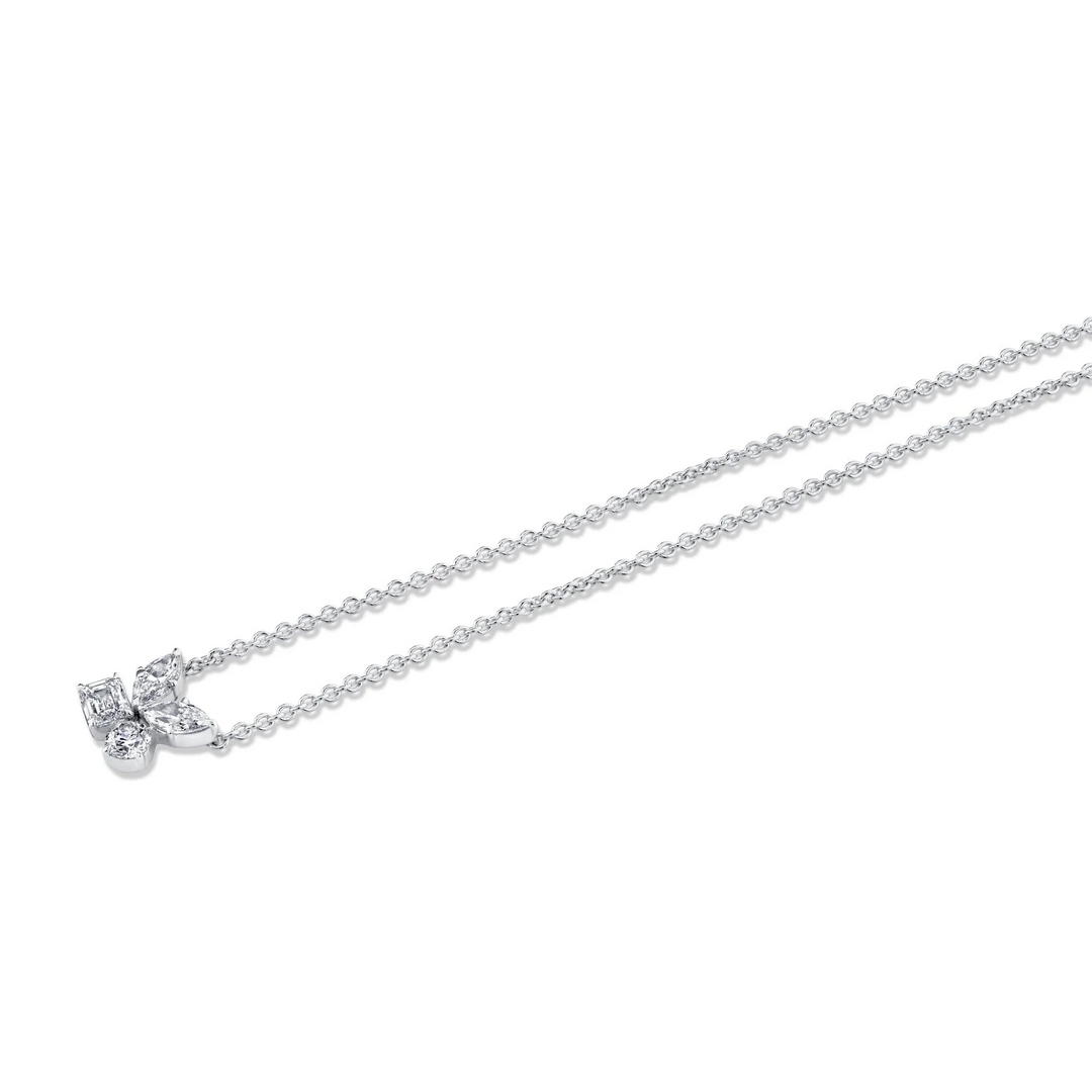 An angled view of a white gold necklace laid out against a white background. The necklace features two marquise, one emerald, and one round-cut diamond cluster design center piece on the necklace.