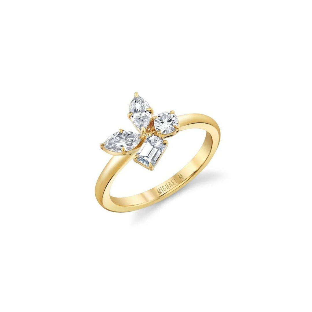 An angled view of a yellow gold ring against a white background. The ring features marquise, pear, and emerald cut stones in a cluster design center piece on a yellow gold band.