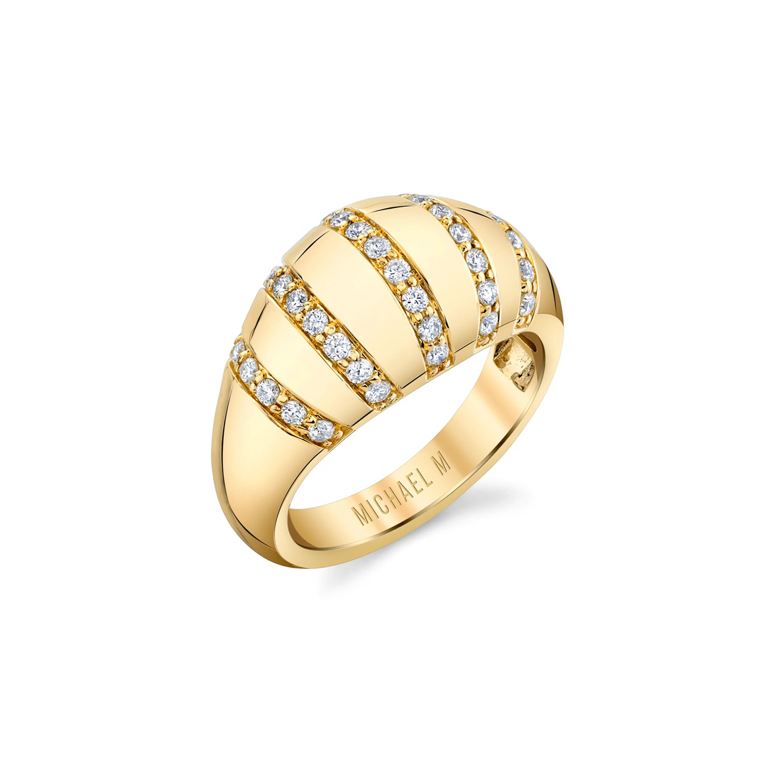 An angled view of a yellow gold diamond ring against a white background. The ring features diamond-set rows of tiny pavé diamonds that line the softly rounded golden surface of the domed signet ring.