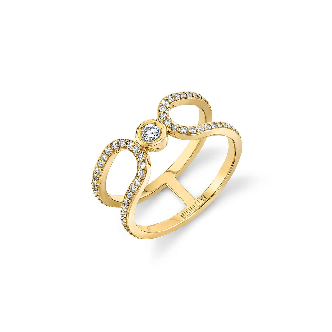 An angled view of a yellow gold wedding band against a white background. The ring features an elongated link that wraps around and squeezes a diamond-set bezel.