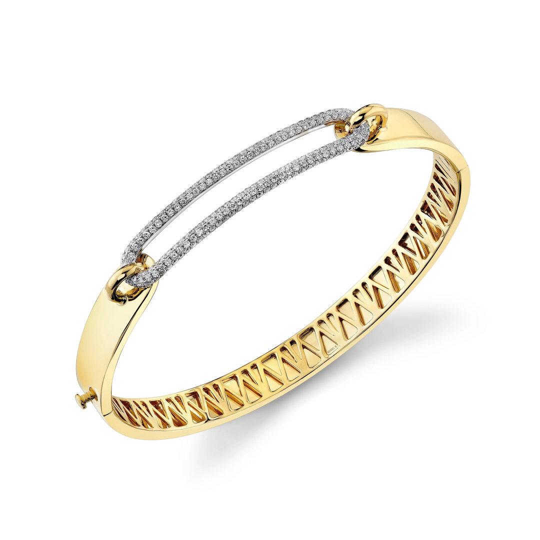 An angled view of a yellow gold bracelet against a white background. The bracelet features a thick gold band and a center link design with pavé-set diamonds, which interlock with the gold band.
