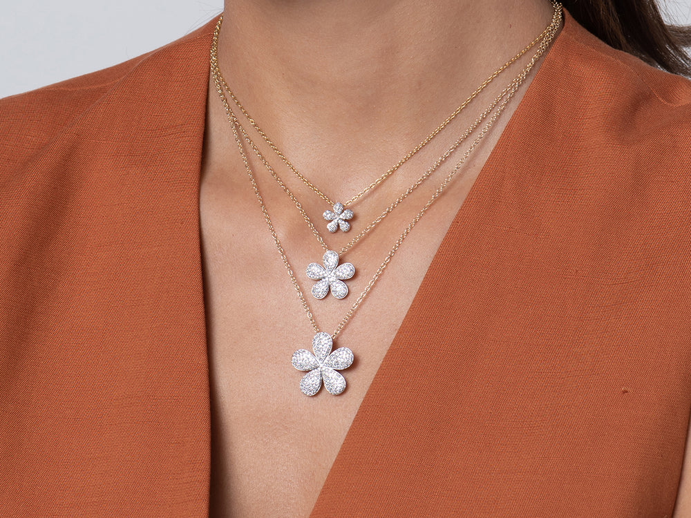 Model wearing three sizes of the Phillips House Forget-Me-Not Necklace, showing the petite diamond flower pendant at the neckline.