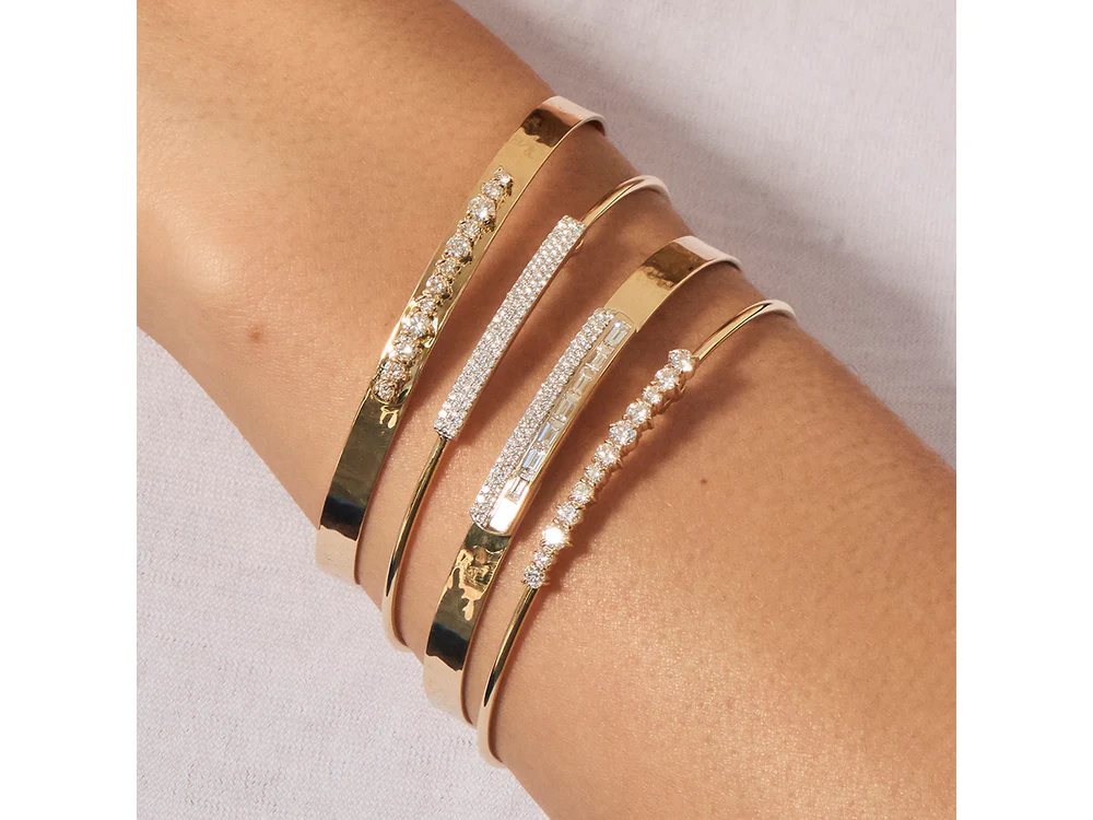 Phillips House Wire Affair Strap Bracelet worn on a model’s wrist, featuring a pavé diamond bar and slim yellow gold band alongside other yellow gold and diamond bracelets.