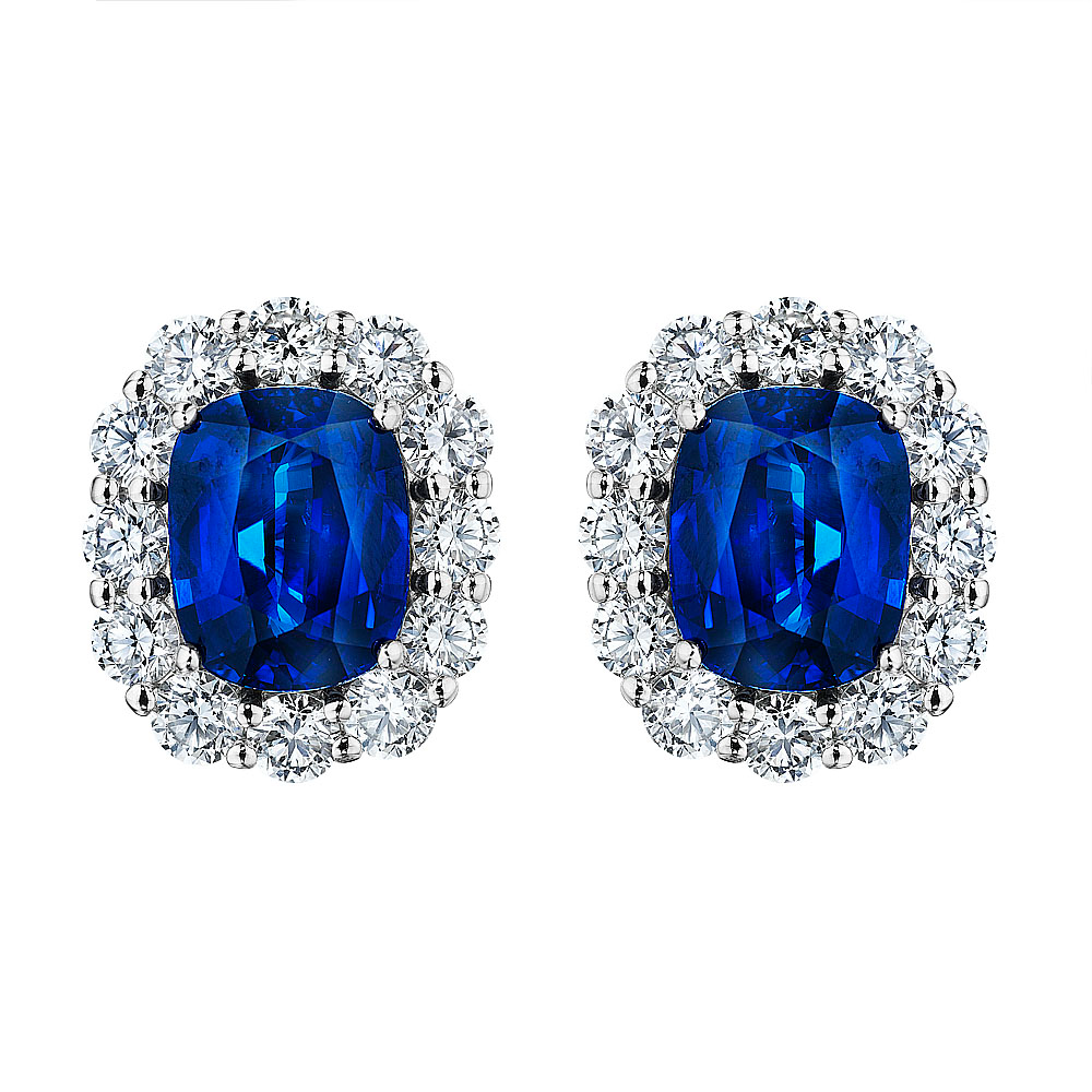 Platinum Diana stud earrings with cushion-cut blue sapphires surrounded by round brilliant diamond halos.