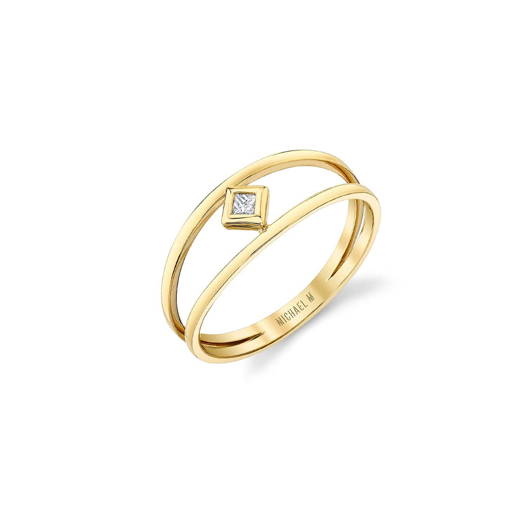 A yellow gold ring is angled to the left in the middle of a white background. The ring features a diamond-set center piece and two yellow-gold rows connecting with Michael M. engraved inside the ring.