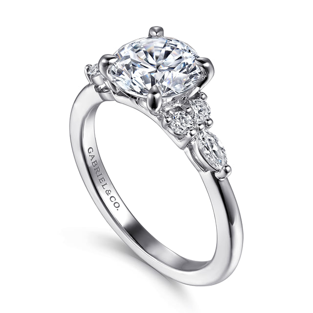 Angled view of a round diamond engagement ring showing clustered side diamonds and a polished 14K white gold band.