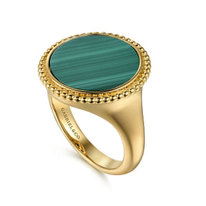 An angled view of a yellow gold ring against a white background. The ring features an inlay of vibrant green malachite gemstone and yellow gold Bujukan beading.