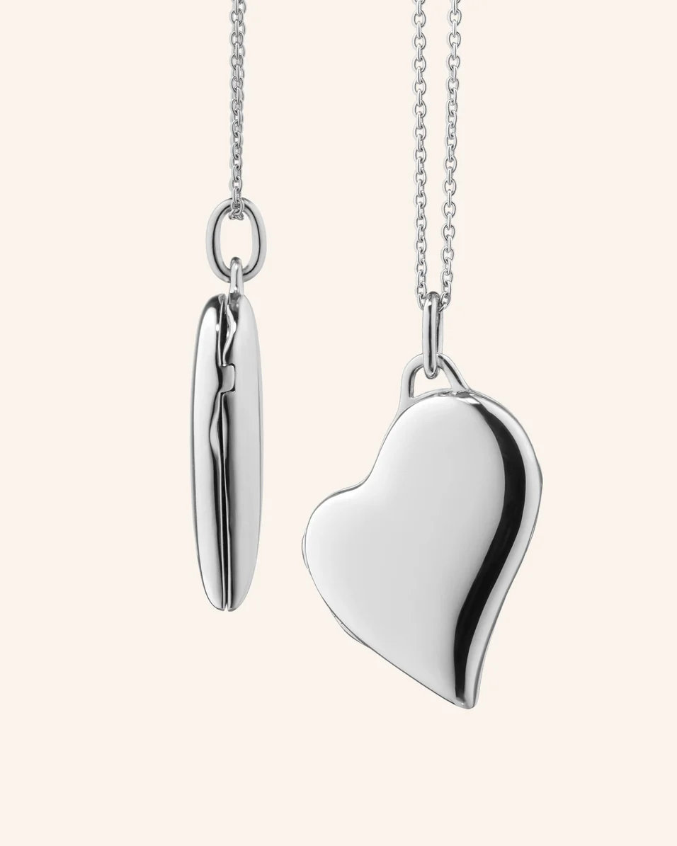 Slim sterling silver heart locket necklace with a polished, off-center heart pendant suspended from a silver chain.