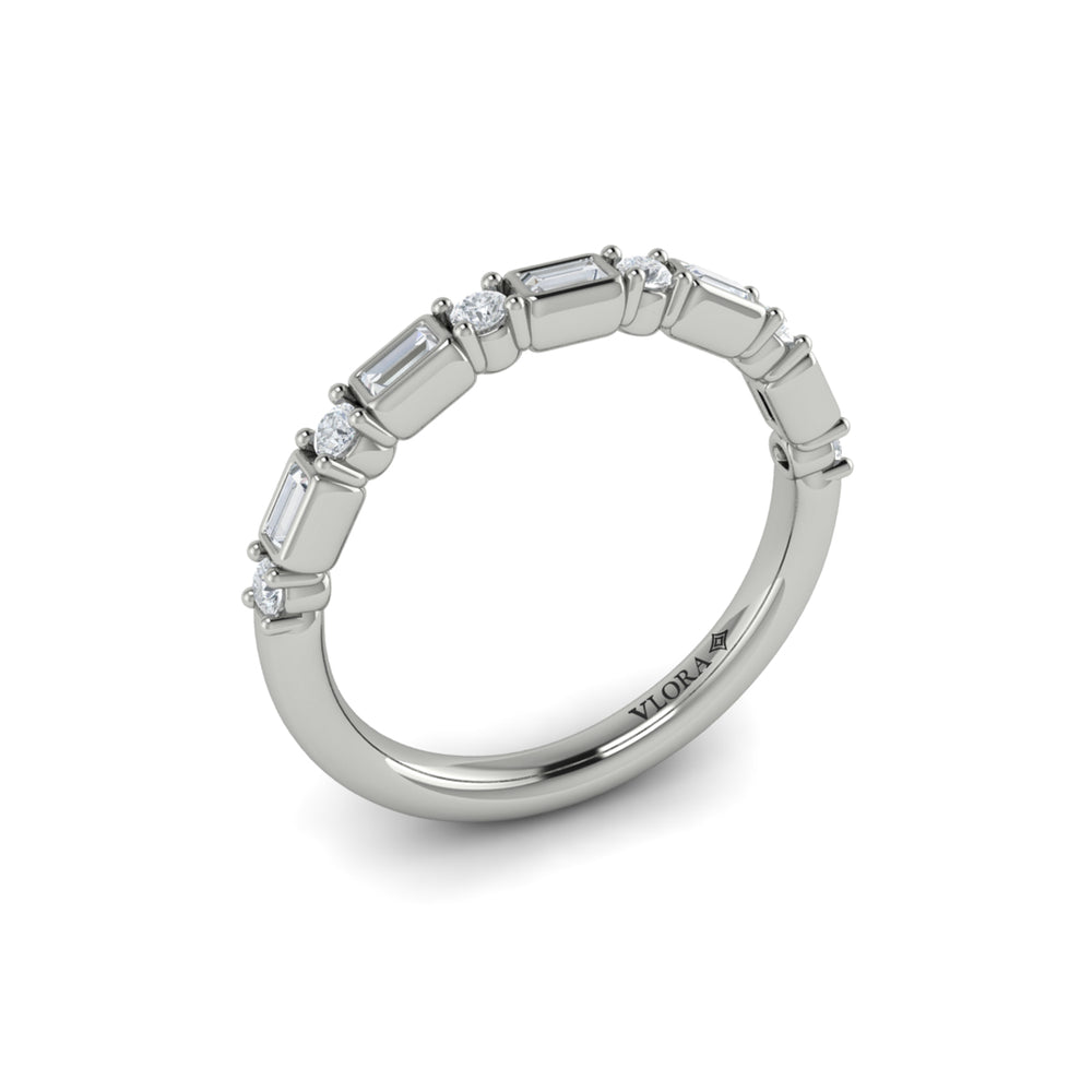 An angled view of a white gold band set against a white background. The ring features a half-eternity east-west emerald and round diamonds alternating design.