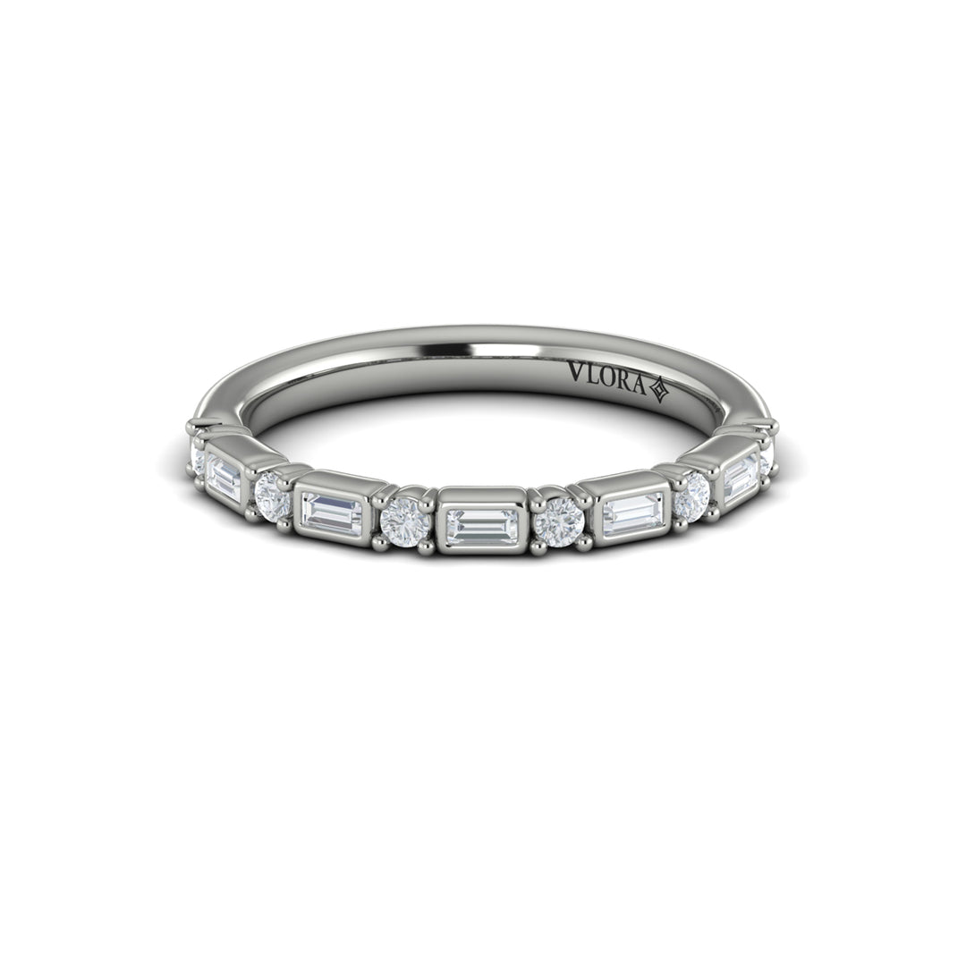 A front view of a white gold band set against a white background. The ring features a half-eternity east-west emerald and round diamonds alternating design.