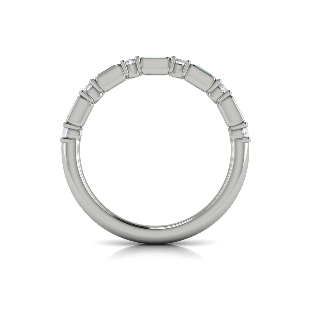 A top view of a white gold band set against a white background. The ring features a half-eternity east-west emerald and round diamonds alternating design.