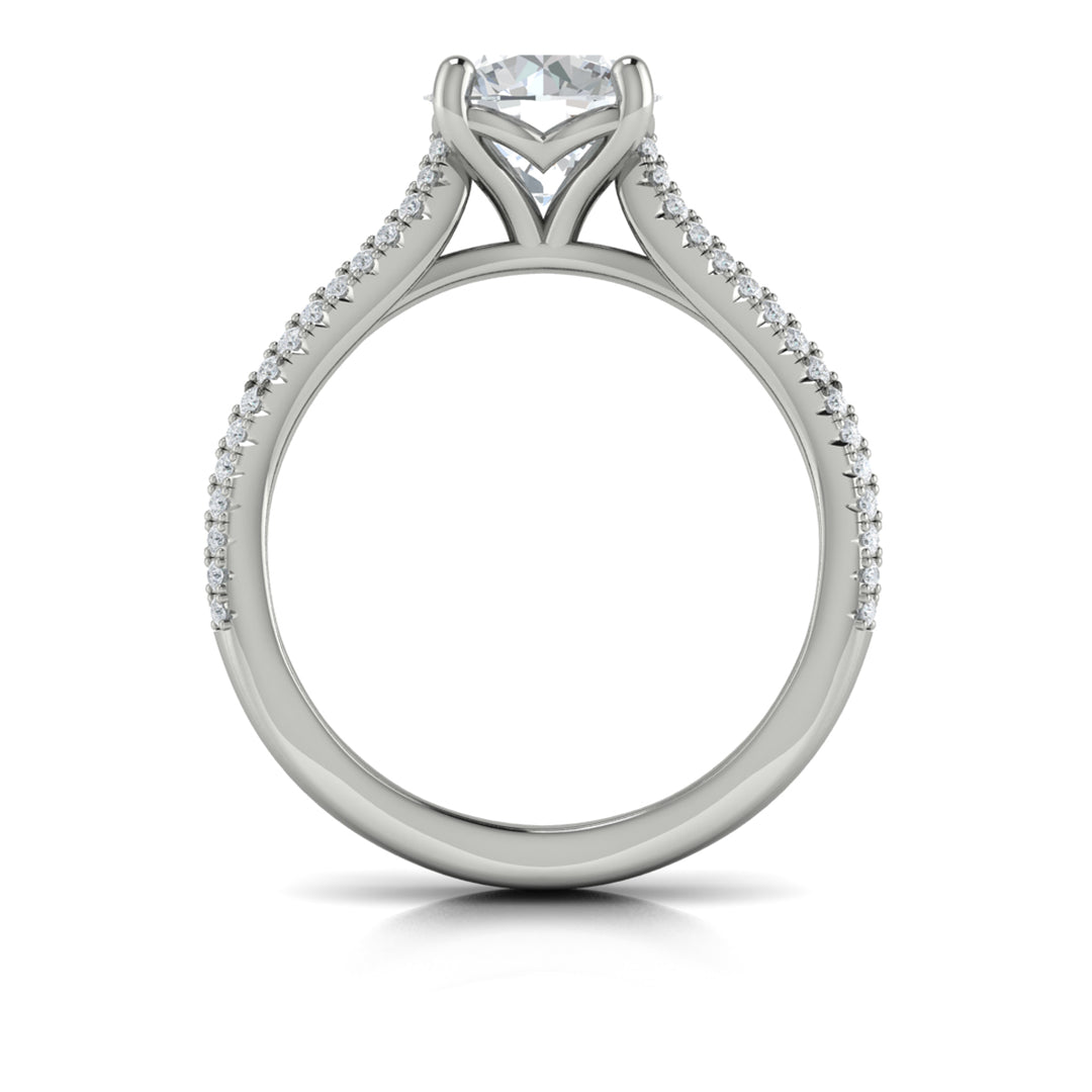 A top view of a white gold engagement ring is set against a white background. The engagement ring features a round center diamond, Vlora's signature V-shaped setting, a three-dimensional channel set baguette diamond band, and a cathedral design.