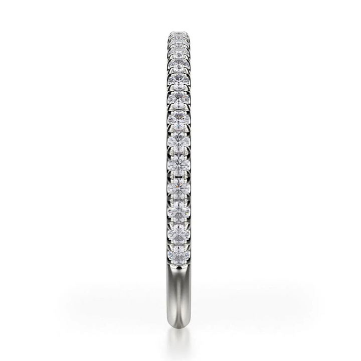 A side-view of a white gold ring in the middle of a white background. The ring features a 3/4 eternity design with round-shaped diamonds set with prongs.