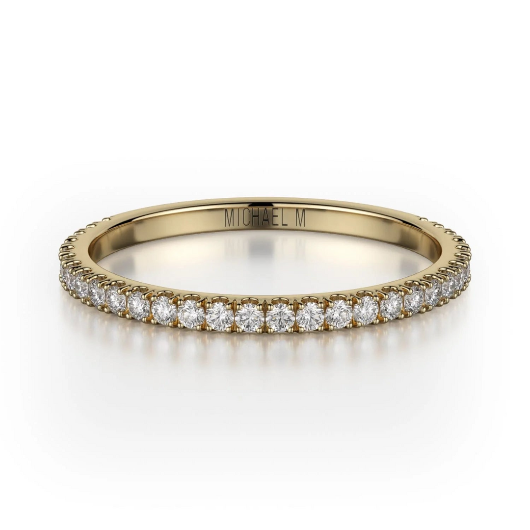 A front view of a yellow gold wedding band against a white background. The ring features a 3/4 eternity style with brilliant round-shaped prong-set diamonds.