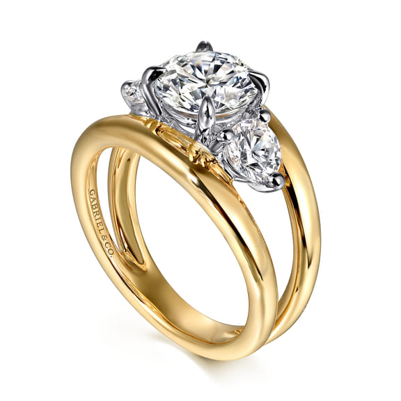 Angled view of a three stone engagement ring showing round diamonds in white gold settings above a polished yellow gold split shank band.