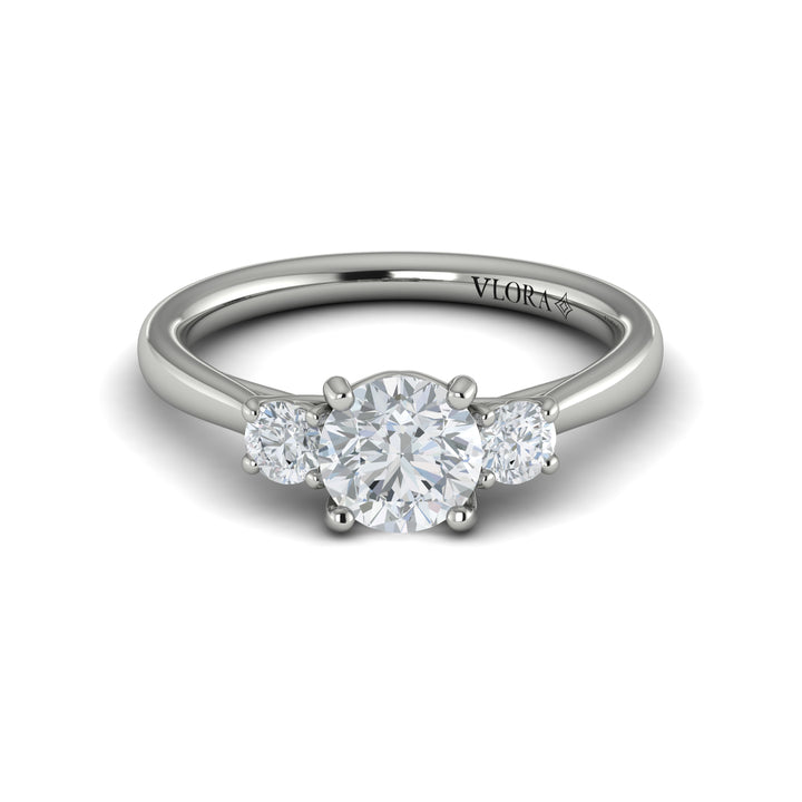 A front view of a white gold engagement ring is set against a white background. The engagement ring features a round center diamond flanked by two smaller round diamonds, set in an interlaced design.