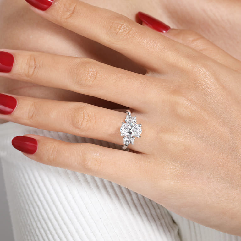 Gabriel & Co. oval three-stone diamond engagement ring in 14K white gold worn on a model’s hand.