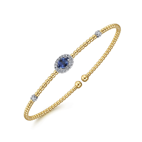 Angled view of the Gabriel & Co Bujukan sapphire bangle showing its raised diamond halo and yellow gold beaded band.