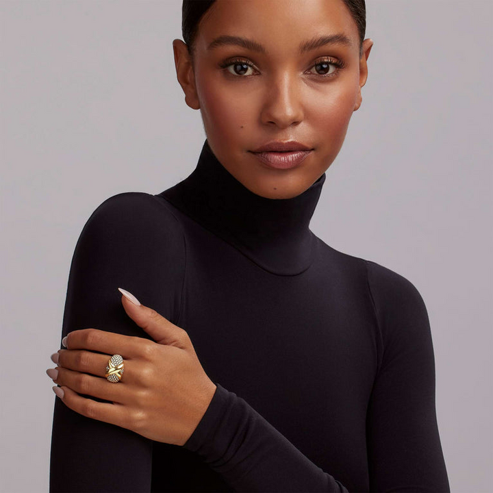 A woman wearing a turtleneck and a two-tone ring on her middle finger. The ring features a two-tone dome-shaped ring with 18K gold and sterling silver caviar beading.