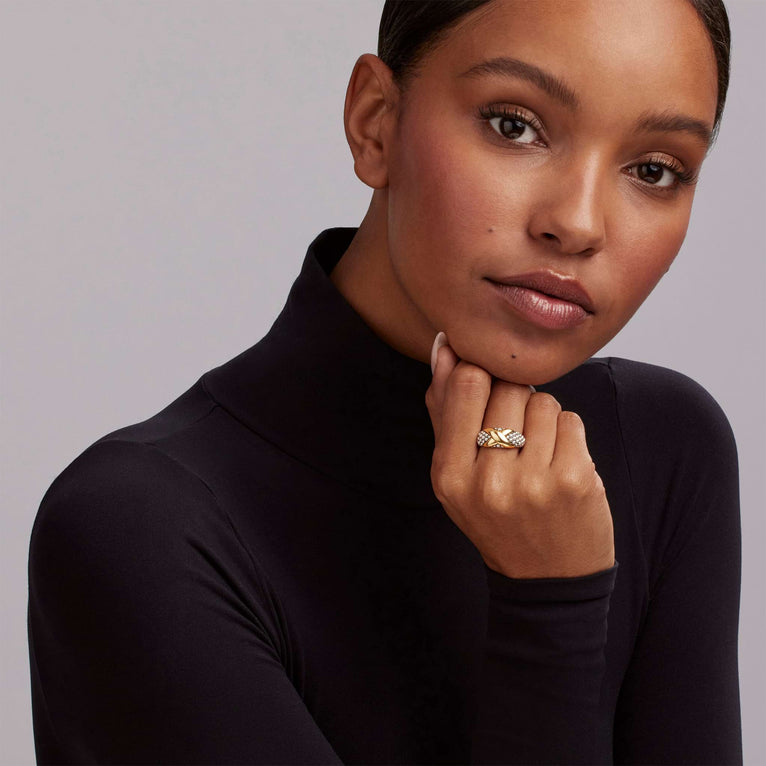 A woman wearing a turtleneck and a two-tone ring on her middle finger. The ring features a two-tone ring with 18K gold and sterling silver caviar beading.